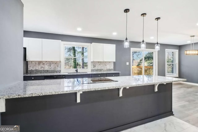 kitchen with white cabinets, backsplash, and decorative light fixtures