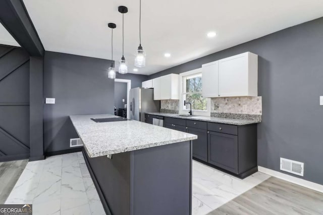 kitchen featuring gray cabinetry, white cabinetry, tasteful backsplash, pendant lighting, and appliances with stainless steel finishes