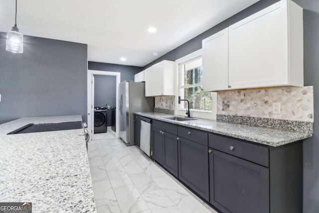 kitchen featuring tasteful backsplash, sink, pendant lighting, white cabinets, and washer / clothes dryer