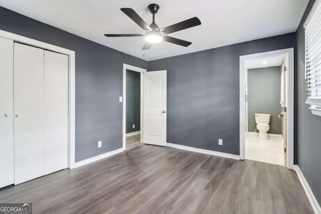 unfurnished bedroom with ceiling fan, dark hardwood / wood-style floors, ensuite bath, and a closet