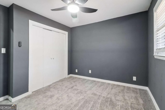 unfurnished bedroom featuring ceiling fan, a closet, and light colored carpet