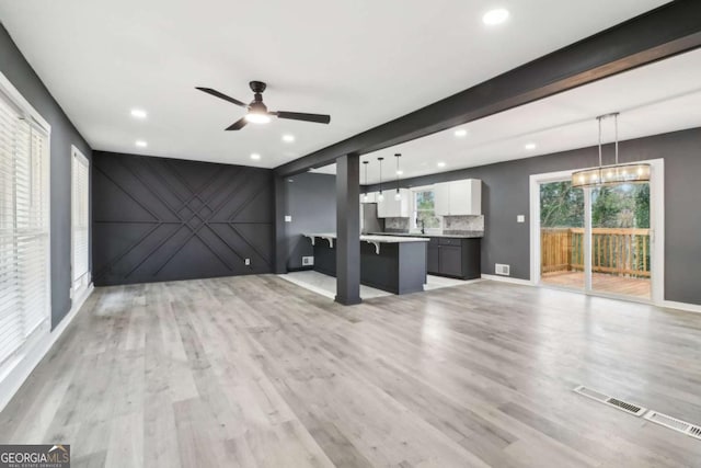 unfurnished living room with light wood-type flooring and ceiling fan