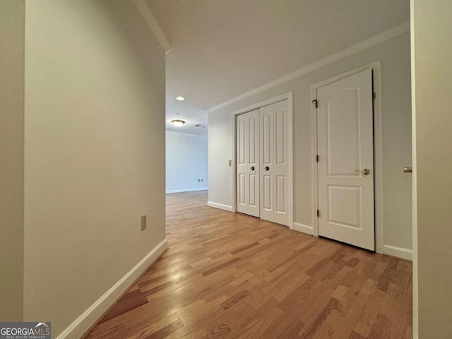 corridor with light hardwood / wood-style floors and crown molding