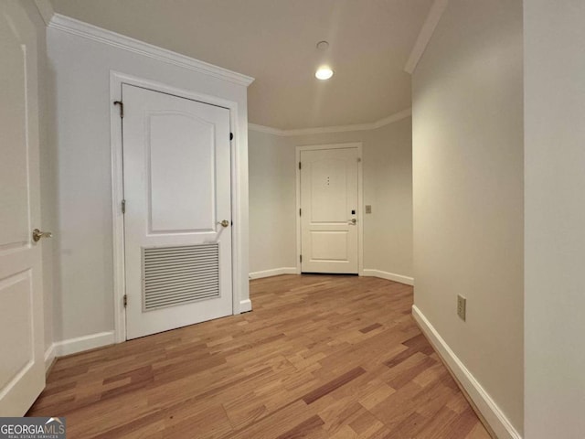 hall with light hardwood / wood-style floors and ornamental molding