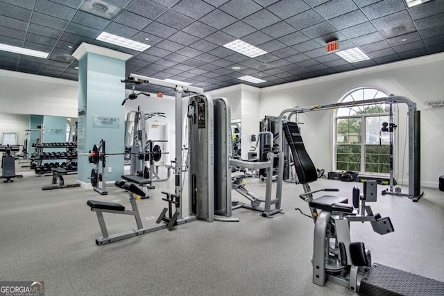 gym with a paneled ceiling and ornamental molding