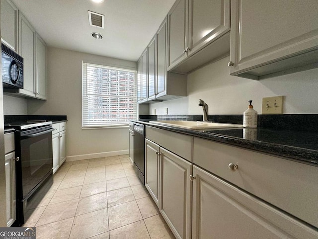 kitchen featuring gray cabinetry, sink, dark stone countertops, light tile patterned floors, and black appliances