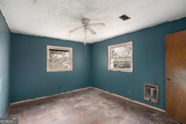 unfurnished room featuring ceiling fan, dark hardwood / wood-style floors, and heating unit