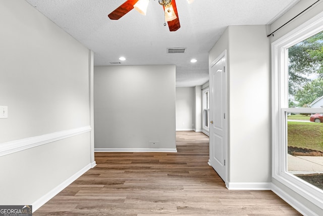 empty room with a textured ceiling, light hardwood / wood-style flooring, and ceiling fan