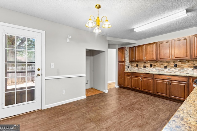 kitchen featuring tasteful backsplash, hanging light fixtures, a textured ceiling, and an inviting chandelier