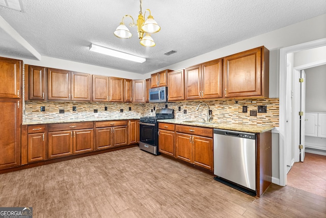 kitchen featuring decorative backsplash, hanging light fixtures, stainless steel appliances, and sink