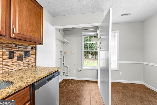 kitchen with dishwasher, backsplash, dark wood-type flooring, a textured ceiling, and light stone counters