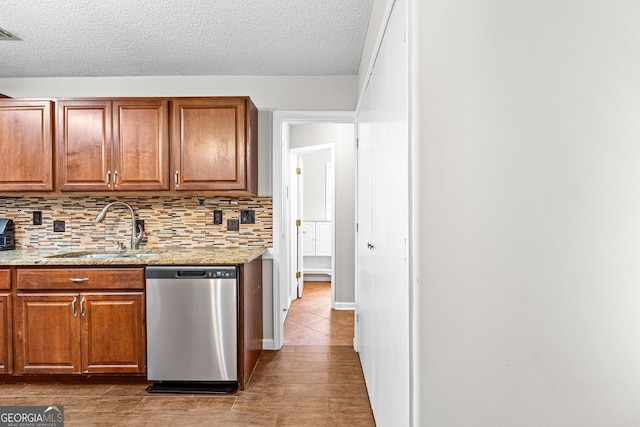 kitchen with decorative backsplash, light stone countertops, a textured ceiling, sink, and dishwasher