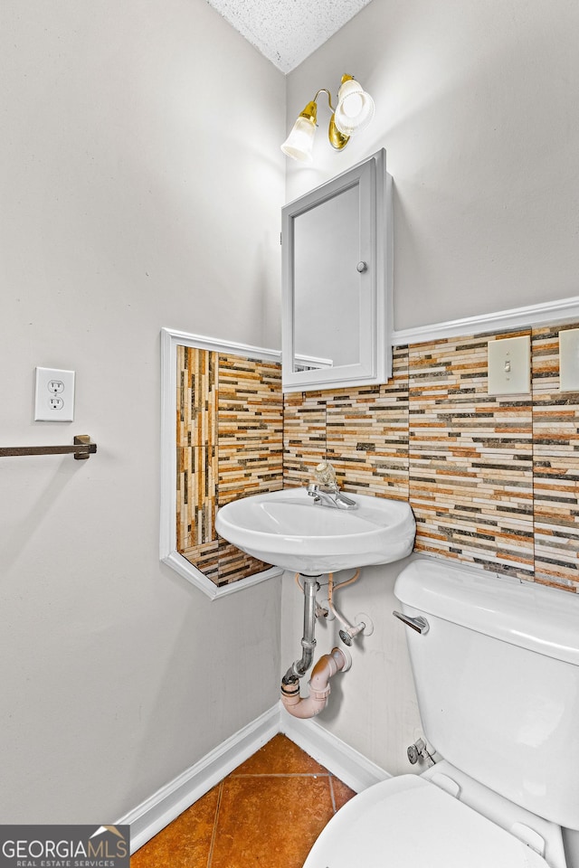 bathroom with sink, tasteful backsplash, tile patterned floors, a textured ceiling, and toilet