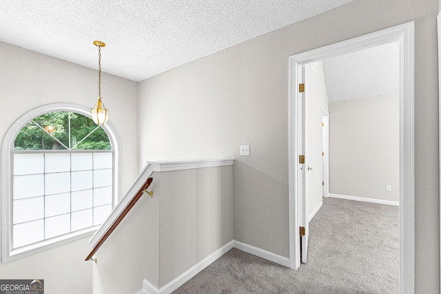 corridor featuring carpet flooring and a textured ceiling