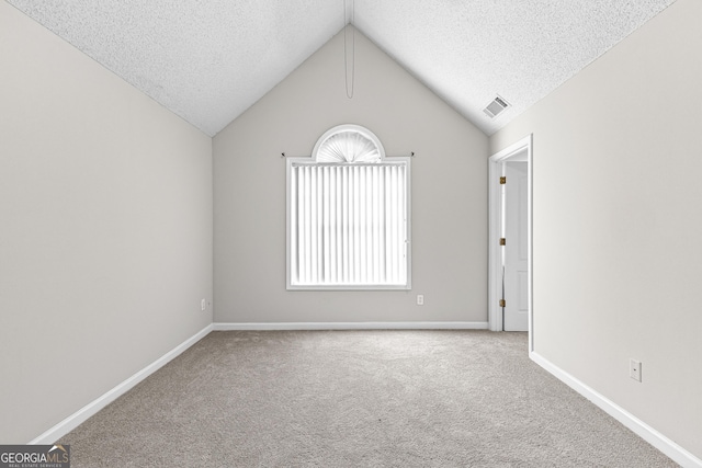 carpeted empty room featuring lofted ceiling and a textured ceiling