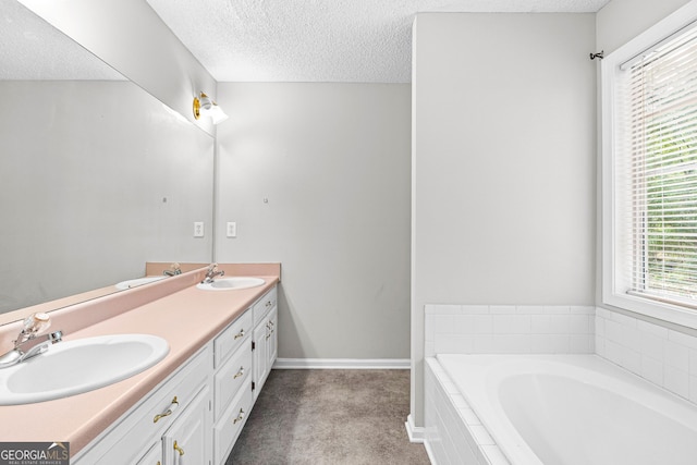 bathroom with vanity, a relaxing tiled tub, and a textured ceiling