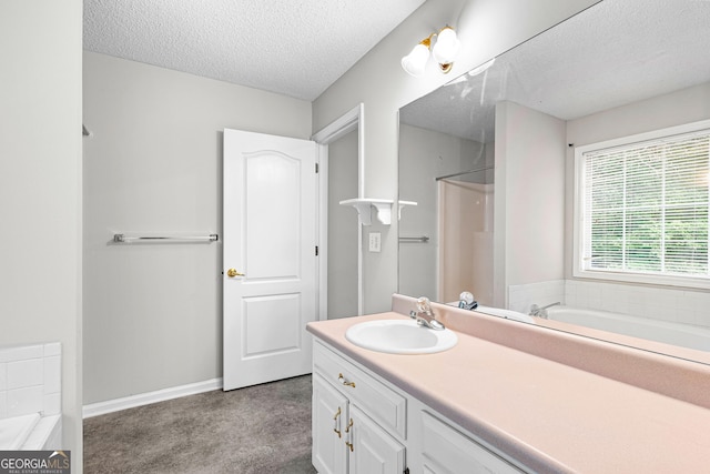 bathroom featuring a tub to relax in, vanity, and a textured ceiling