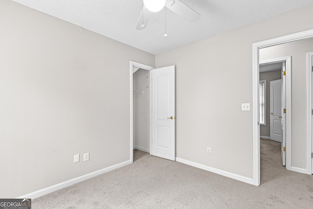 unfurnished bedroom with a textured ceiling, ceiling fan, and light carpet