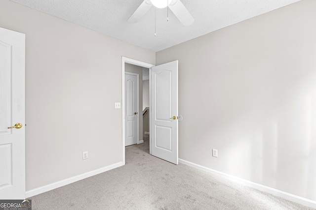 unfurnished bedroom featuring ceiling fan, light carpet, and a textured ceiling