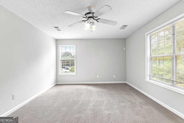 carpeted spare room with a textured ceiling and ceiling fan