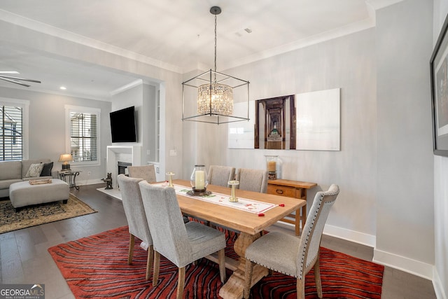 dining room featuring ceiling fan with notable chandelier, dark wood-type flooring, and crown molding