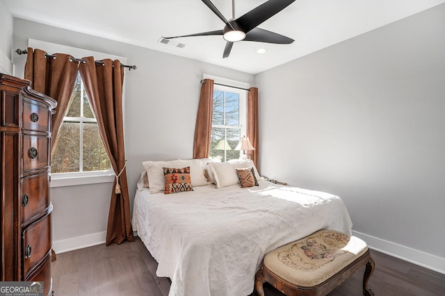 bedroom with multiple windows, dark hardwood / wood-style flooring, and ceiling fan