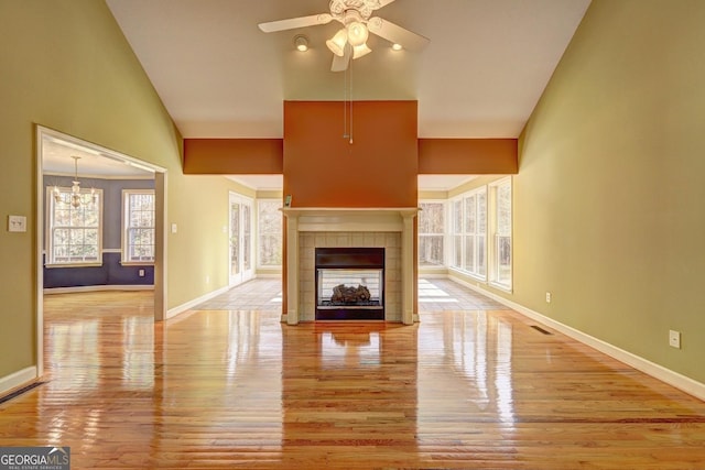 unfurnished living room featuring a fireplace, ceiling fan with notable chandelier, and light hardwood / wood-style flooring