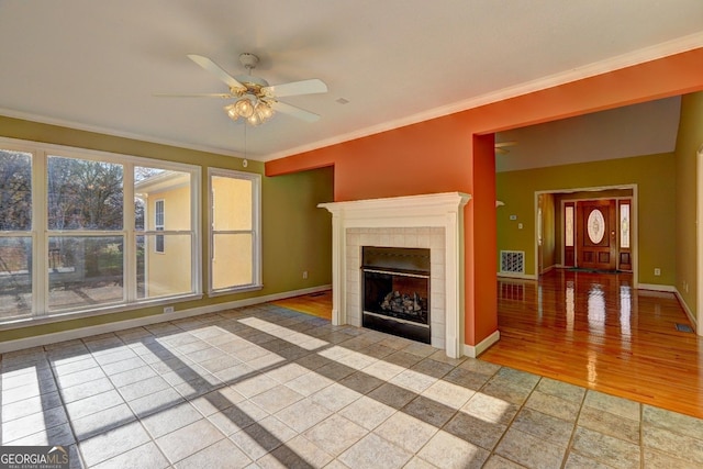 unfurnished living room with tile patterned flooring, ceiling fan, ornamental molding, and a tiled fireplace