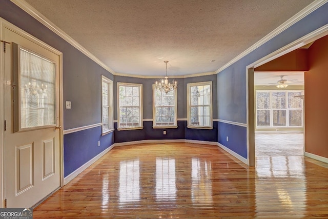 unfurnished dining area with ceiling fan with notable chandelier, light wood-type flooring, a textured ceiling, and crown molding