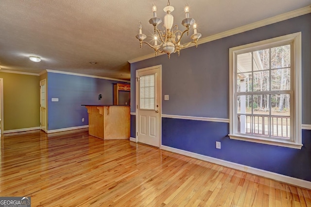 interior space with crown molding, light hardwood / wood-style floors, and an inviting chandelier