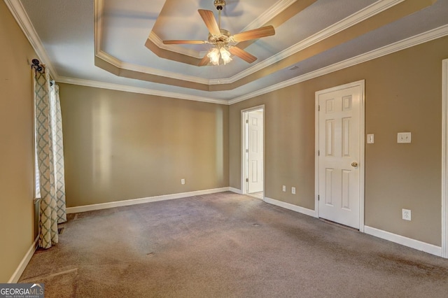 carpeted spare room featuring a raised ceiling, ceiling fan, and ornamental molding