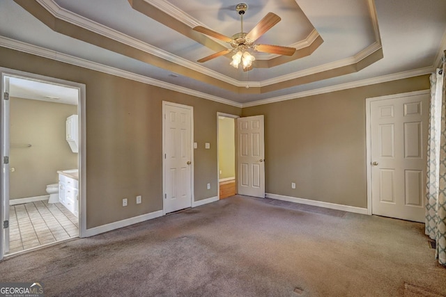 unfurnished bedroom with light carpet, ensuite bath, ceiling fan, ornamental molding, and a tray ceiling