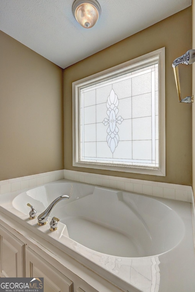 bathroom featuring a bathing tub, plenty of natural light, and a textured ceiling