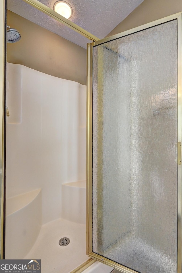 bathroom featuring a shower with door and a textured ceiling