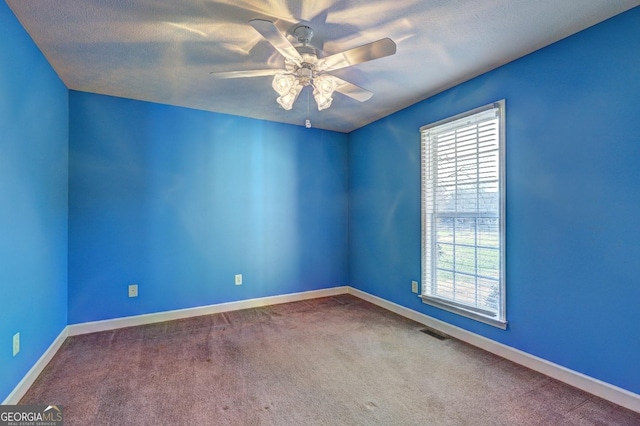 empty room with carpet flooring, ceiling fan, and a textured ceiling