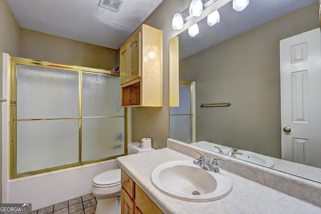 full bathroom with tile patterned floors, vanity, a textured ceiling, shower / bath combination with glass door, and toilet