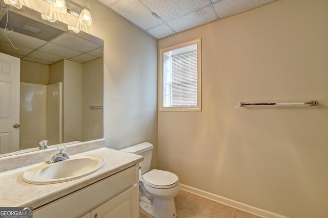 bathroom with tile patterned floors, a drop ceiling, vanity, and toilet