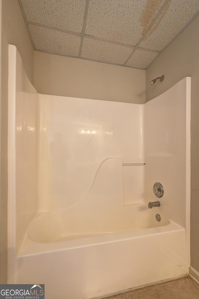 bathroom with a paneled ceiling, tile patterned floors, and shower / washtub combination