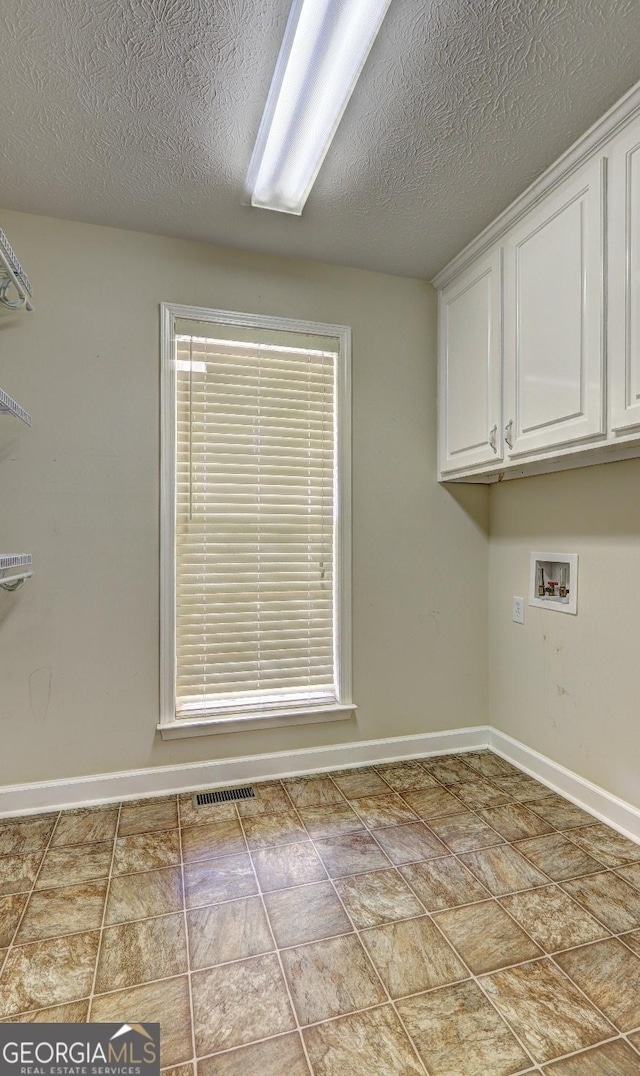 washroom featuring washer hookup, cabinets, and a textured ceiling