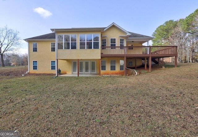 back of house featuring a lawn, a sunroom, a patio, and a wooden deck