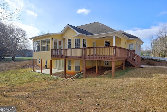 back of property with a yard, a wooden deck, a patio area, and a sunroom