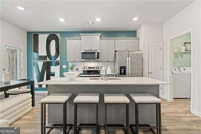 kitchen with stainless steel dishwasher, ceiling fan, sink, gray cabinets, and an island with sink