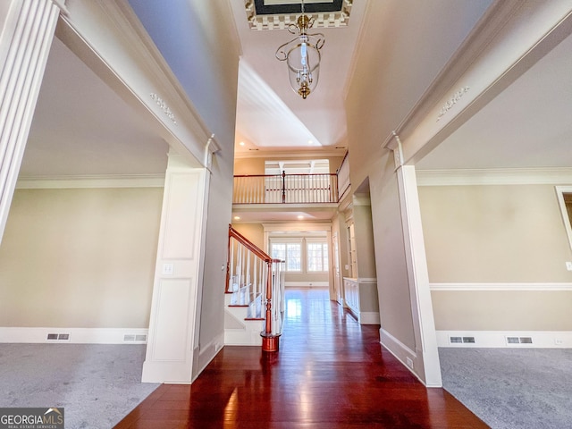 entrance foyer with dark hardwood / wood-style flooring, a towering ceiling, and ornamental molding