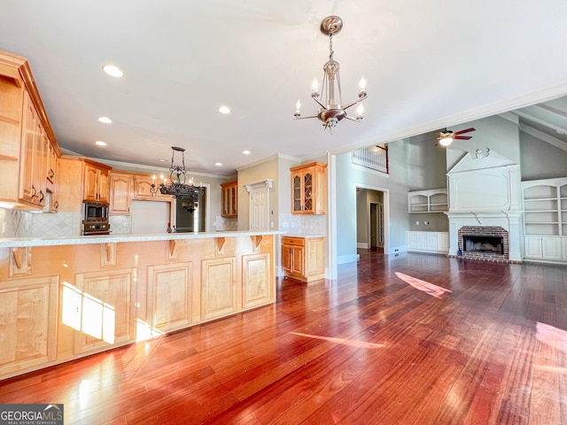 kitchen featuring tasteful backsplash, stainless steel appliances, ceiling fan with notable chandelier, and a breakfast bar area