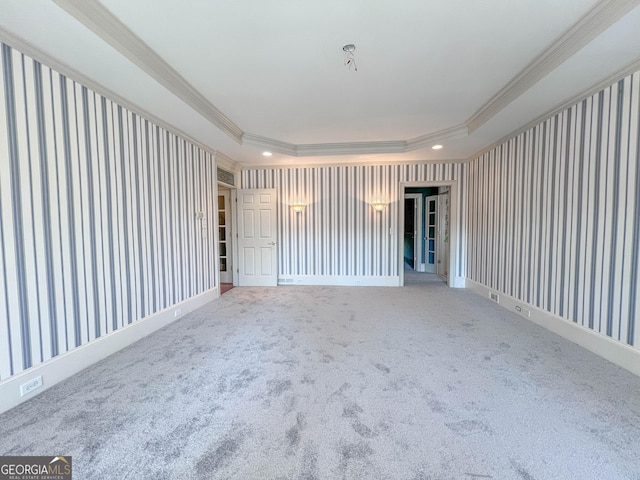 carpeted spare room with ornamental molding and a raised ceiling