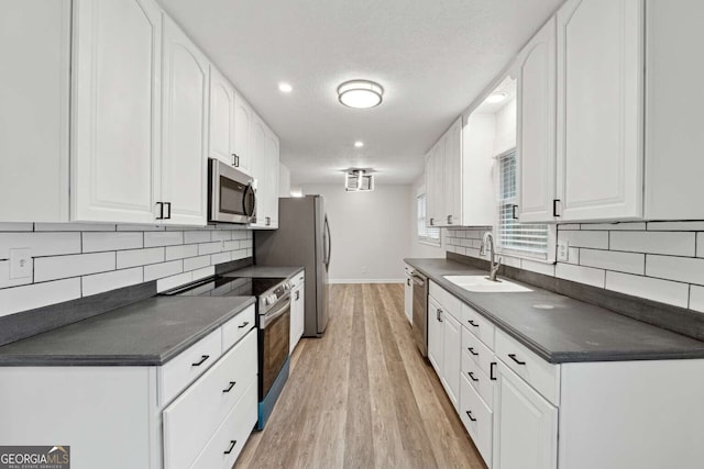 kitchen featuring white cabinets, sink, light wood-type flooring, a textured ceiling, and appliances with stainless steel finishes