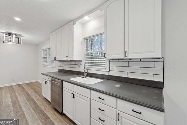 kitchen featuring white cabinets, decorative backsplash, and dishwasher