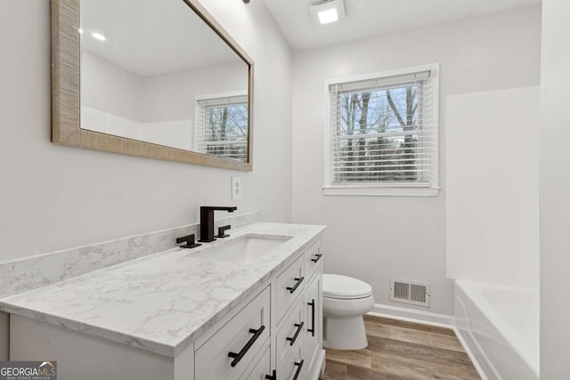 bathroom with a bathtub, toilet, vanity, and hardwood / wood-style flooring