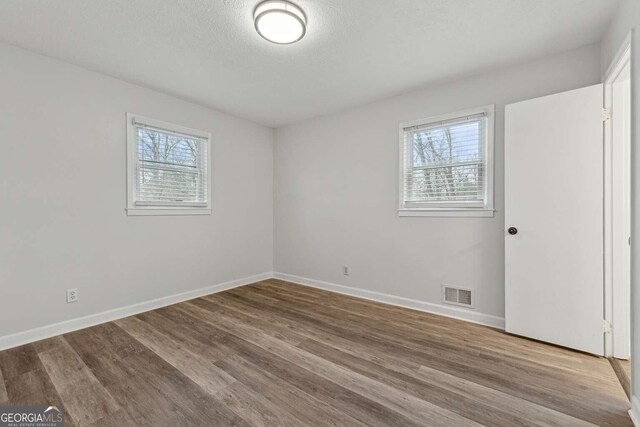 spare room featuring hardwood / wood-style flooring, a healthy amount of sunlight, and a textured ceiling