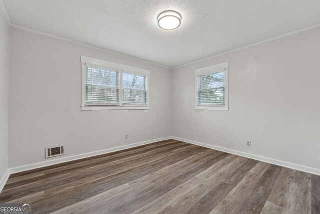 unfurnished room featuring crown molding, dark wood-type flooring, and a textured ceiling